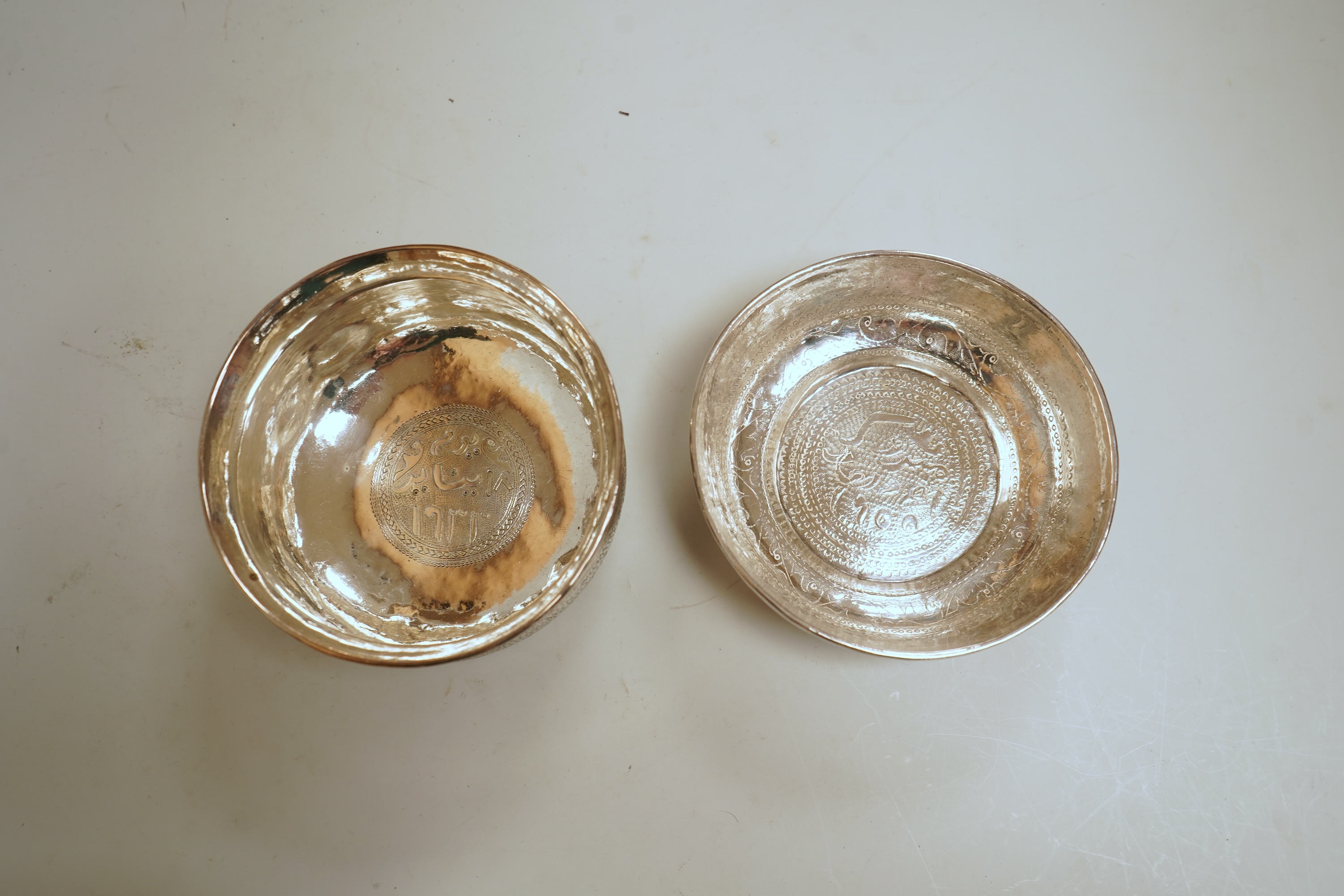 Two early to mid 20th century Persian engraved white metal bowls, both diameters approximately 11.5cm.